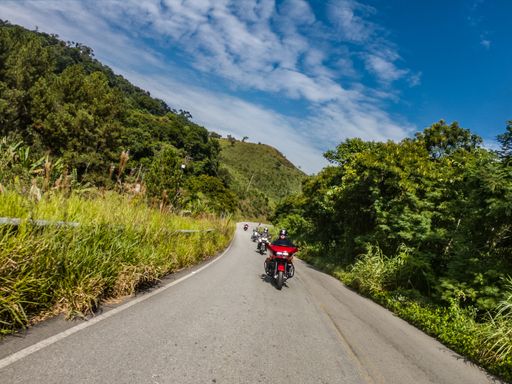 A shot of bikers going down a country road under the cloudy sky