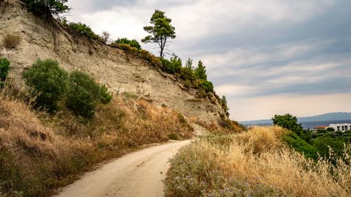 A dirt road up on a hill in the countryside under a cloudy sky