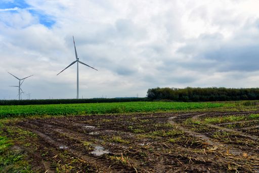 A country scenery after the rain with wind turbines standing in a greenfield