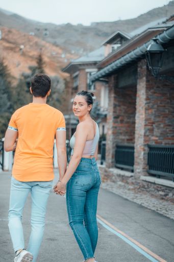A portrait of a Caucasian male and female walking while holding hands on a road