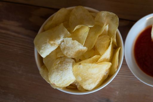 A top view of a bowl of potato chips on a wooden table