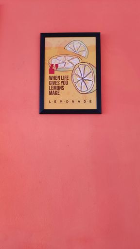 A vertical shot of a motivational life lemon poster on a pink wall