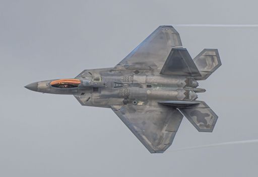 A low angle shot of a F-22 Raptor jet flying in the sky