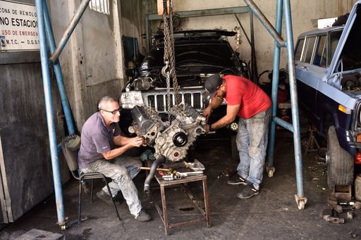 A father and son work together in their garage repairing a V8 engine
