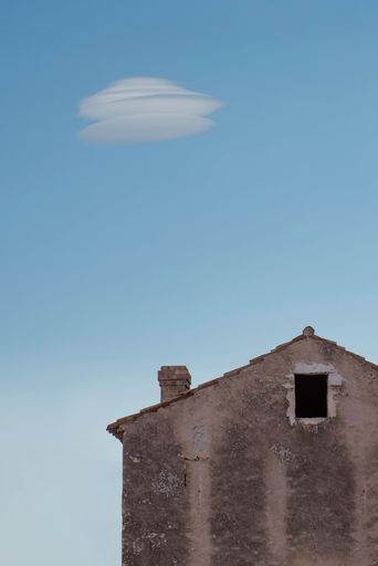 A vertical shot of an old abandoned stone house against a blue sky