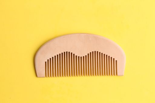 A top view of a wooden comb on a yellow background