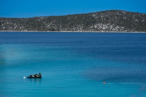 A beautiful view of Adriatic Sea with a jet ski and a swimming man in it at Primosten in municipality in Croatia