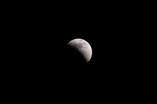 The lunar eclipse full crescent super moon rising against the dark sky