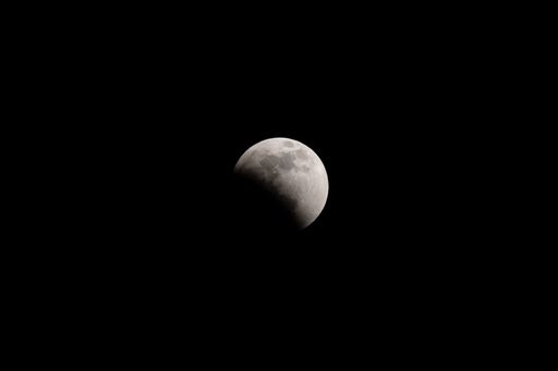 The lunar eclipse full crescent super moon rising against the dark sky