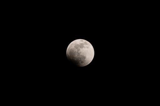 The lunar eclipse full crescent super moon rising against the dark sky