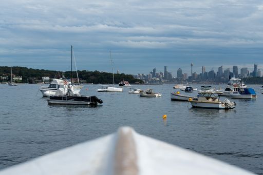A scenic view of boats sailing in a blue sea against cityscape in Australia