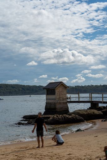 A vertical shot of Caucasian people on a sandy beach against a wooden construction on the water