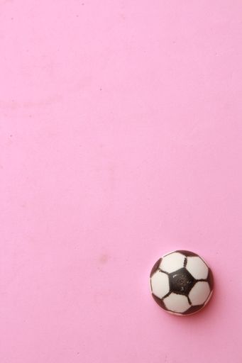 A vertical shot of a small football ball isolated on a pink background