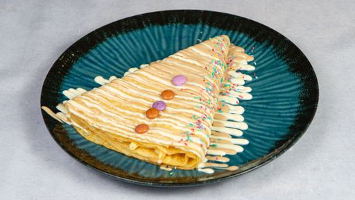 A tasty crepe drizzled with chocolate on a plate