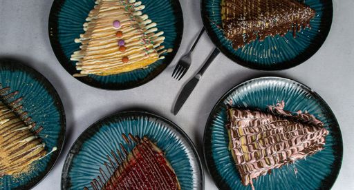 A closeup shot of tasty crepe drizzled with chocolate on plates