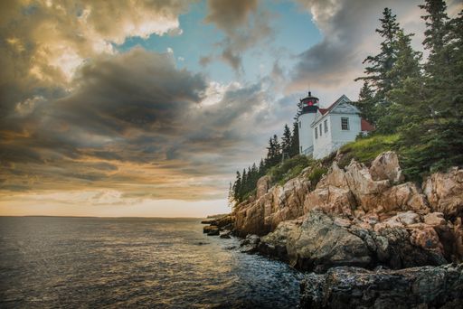 A beautiful shot of a white house on top of the cliff on the edge of the ocean under the cloudy sky