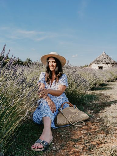 A vertical shot of a beautiful young Caucasian woman in a straw hat in a lavender field