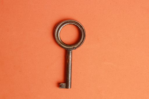 An isolated high angle top view closeup shot of a rusty metal key on an orange table