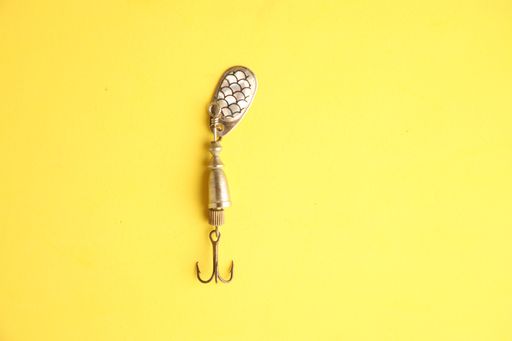 A top view of a single fishing lure on a yellow background