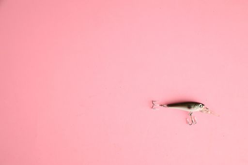A high angle shot of a fishing lure isolated on a pink surface