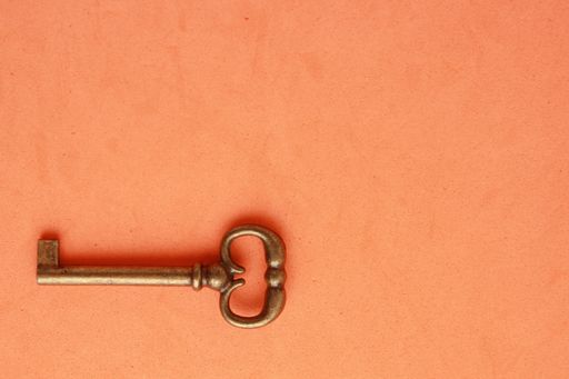 A high angle closeup shot of a vintage closet key on an orange background