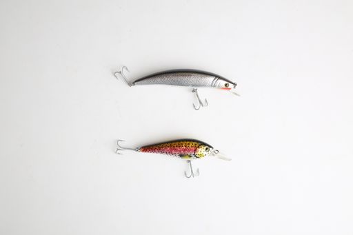 A high angle closeup shot of two fish-shaped fishing lures on a white background