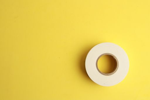 A top view of a tape roll under the lights on a yellow surface