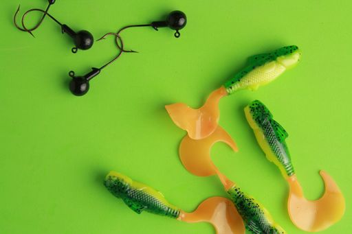 A top view of colorful different fishing lures and hooks on a green background