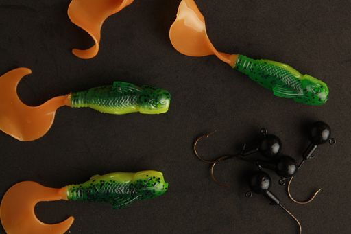 A top view of different colorful fishing lures on a dark surface