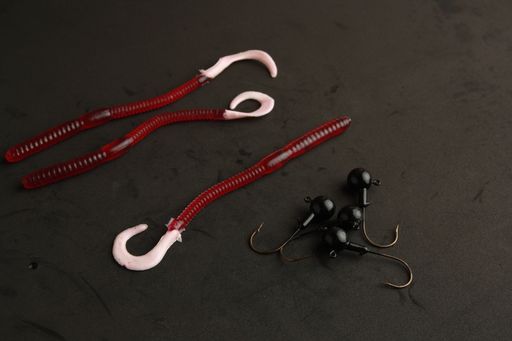 A closeup of colorful different fishing lures and hooks on a black background