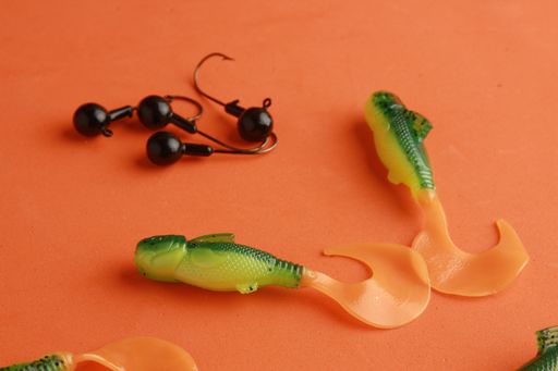 A closeup shot of plastic fishing lures on an orange background