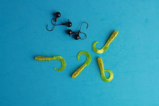 A top view of colorful different fishing lures and hooks on a blue background
