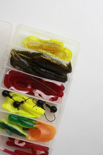 A top view of fishing lure sets in a plastic box on a white background