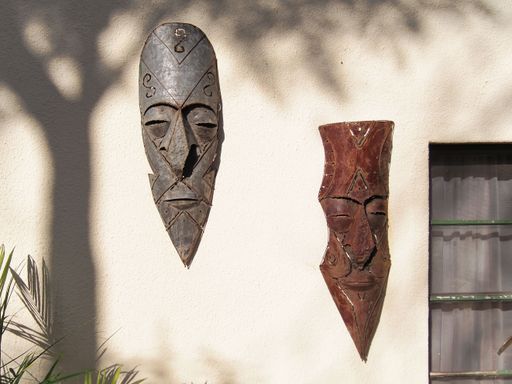 A closeup of two traditional African wooden masks hanging on the exterior of a wall in Namibia, Africa