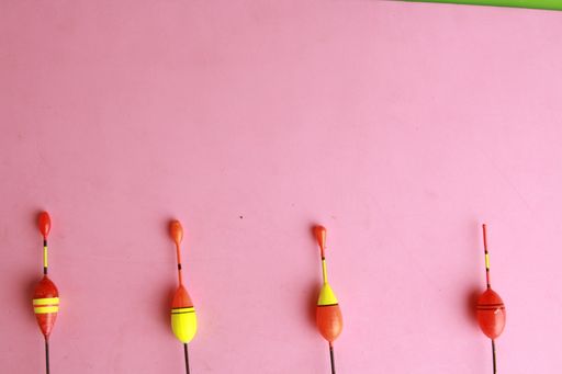 A flat lay shot of fishing floats on a pink surface