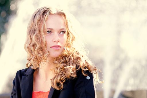 A shallow focus shot of a curly blonde model with hazel eyes with a thoughtful facial expression