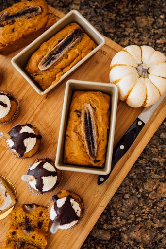 A vertical high angle shot of pumpkin bread and fall treats on a wooden surface
