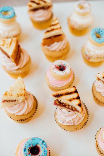 A vertical high angle shot of different kinds of cupcakes on white surface