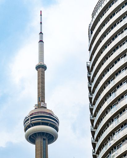 A vertical shot of the CN Tower against blue cloudy sky background in Toronto, Ontario, Canada