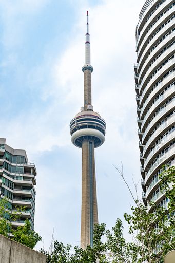 A vertical shot of the CN Tower against blue cloudy sky background in Toronto, Ontario, Canada