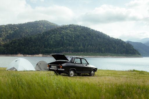 An old retro car parked near a rural lake shore in Arad, Romania
