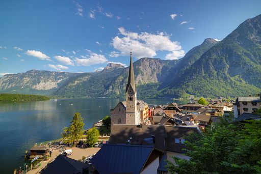 A scenic shot of The Hallstatt Lutheran Church and the cityscape of Salzburg with a river and mountains in the background.