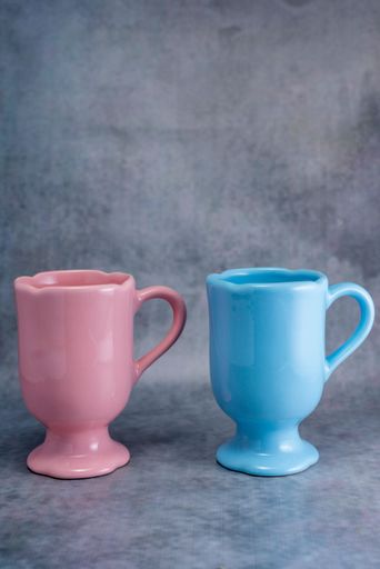 A vertical shot of a pink mug and a blue mug isolated on a gray background