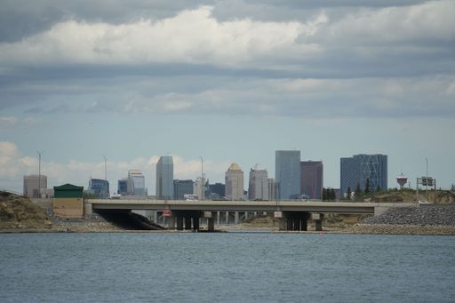 A beautiful shot of a bridge over river and many modern buildings in background under cloudy sky
