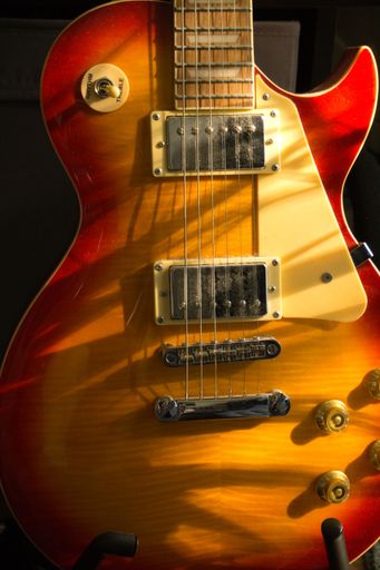 A vertical shot of a colorful electric guitar in sunlight