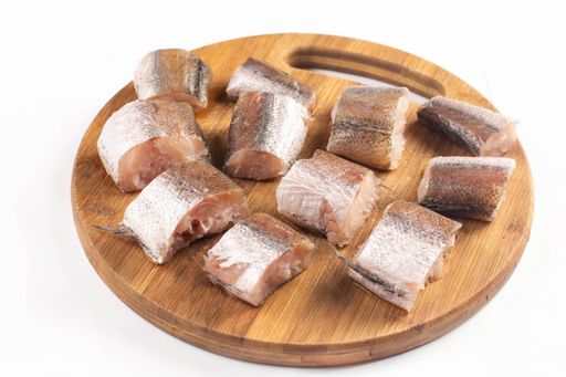 A close-up shot of sliced Hake fish on a wooden board isolated on white background