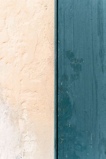 A vertical closeup shot of a plain cream-colored wall meeting a blue wooden door