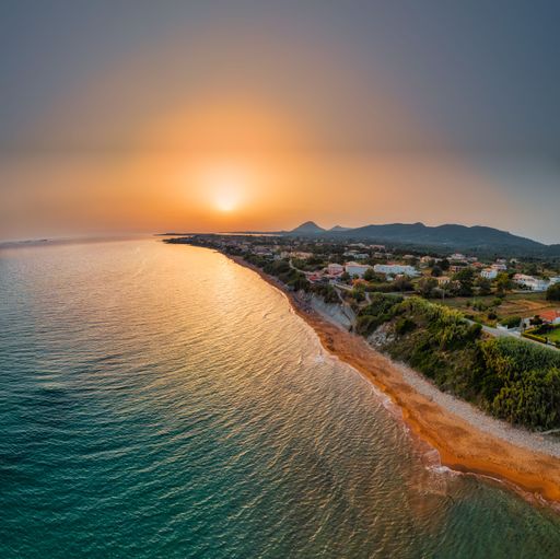 A scenic aerial view of the seashore and mountains during sunset
