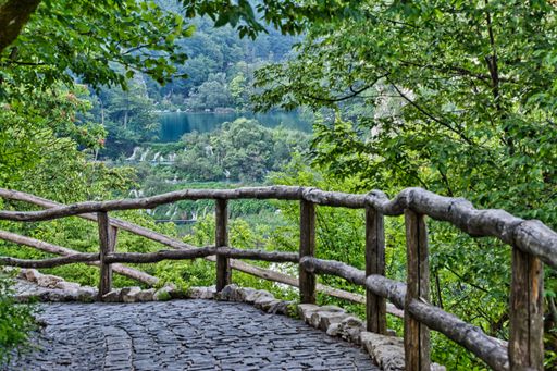 The wooden fence of winding cobblestone trail in the woods