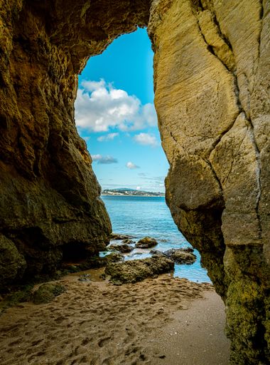 A vertical shot of the beach and sky spotted from inside the cave